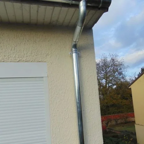 Witte gevel met nieuwe regenpijp onder de dakoversteek