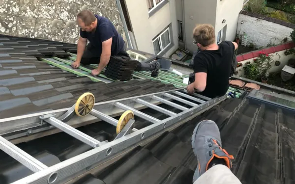 Dakwerkers aan het werk op het hellende dak van een rijwoning