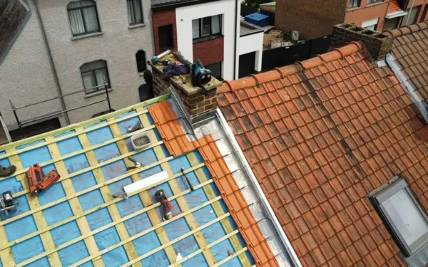 Rood pannendak deels open met nieuw onderdak en panlatten naast de schoorsteen